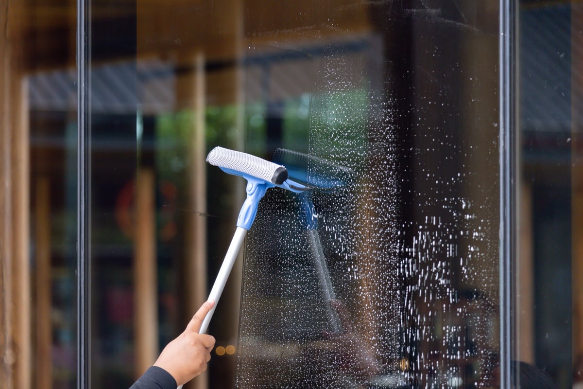 Person cleaning a window with a squeegee for a clear bright finish